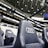 A row of black leather stadium seats with the Audi logo prominently displayed in an upscale sports venue. In the background, there are large screens and bright signage displaying the words 'The game is about glory,' suggesting a high-profile sporting event location.