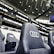 A row of black leather stadium seats with the Audi logo prominently displayed in an upscale sports venue. In the background, there are large screens and bright signage displaying the words 'The game is about glory,' suggesting a high-profile sporting event location.